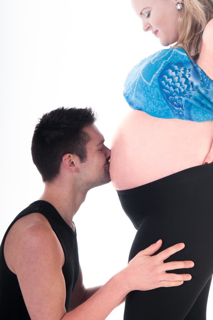 husband kissing baby bump