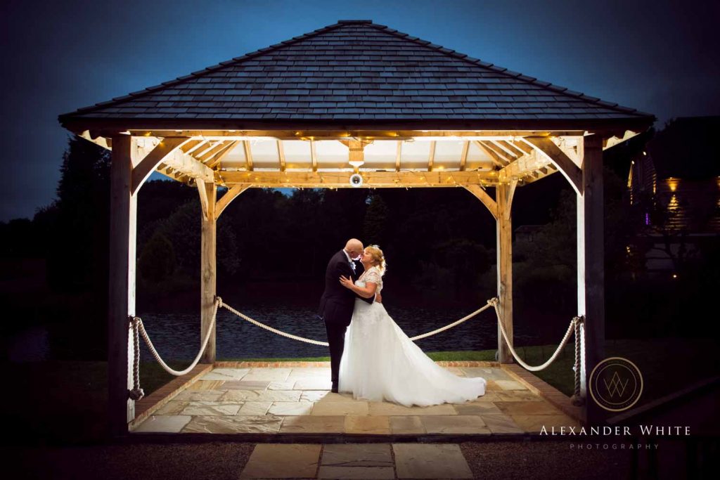 Brookfield Barn outdoor wedding venue in Horsham West Sussex Wedding photo of couple backlit under a shelter at dusk