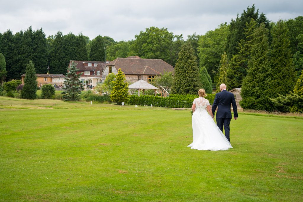 Wedding photo of a couple walking on a golf green at Brookfield Barn near Horsham
