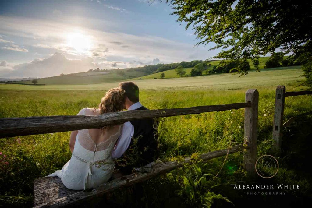 Bride and Groom cuddling up and watching the sunset over East Dean Village in the South Downs