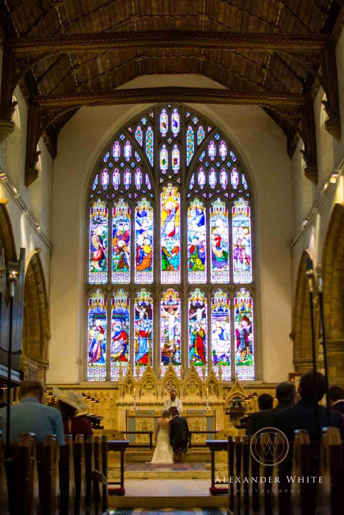 Internal view of Horsham's StMary's Church with the wedding in progress looking at it's large stained glass window