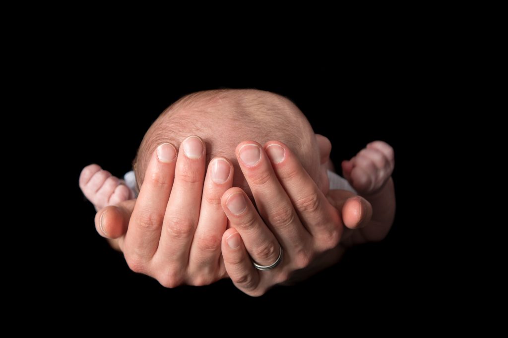 A photo from the top of a baby's head as it is held in his father's hands