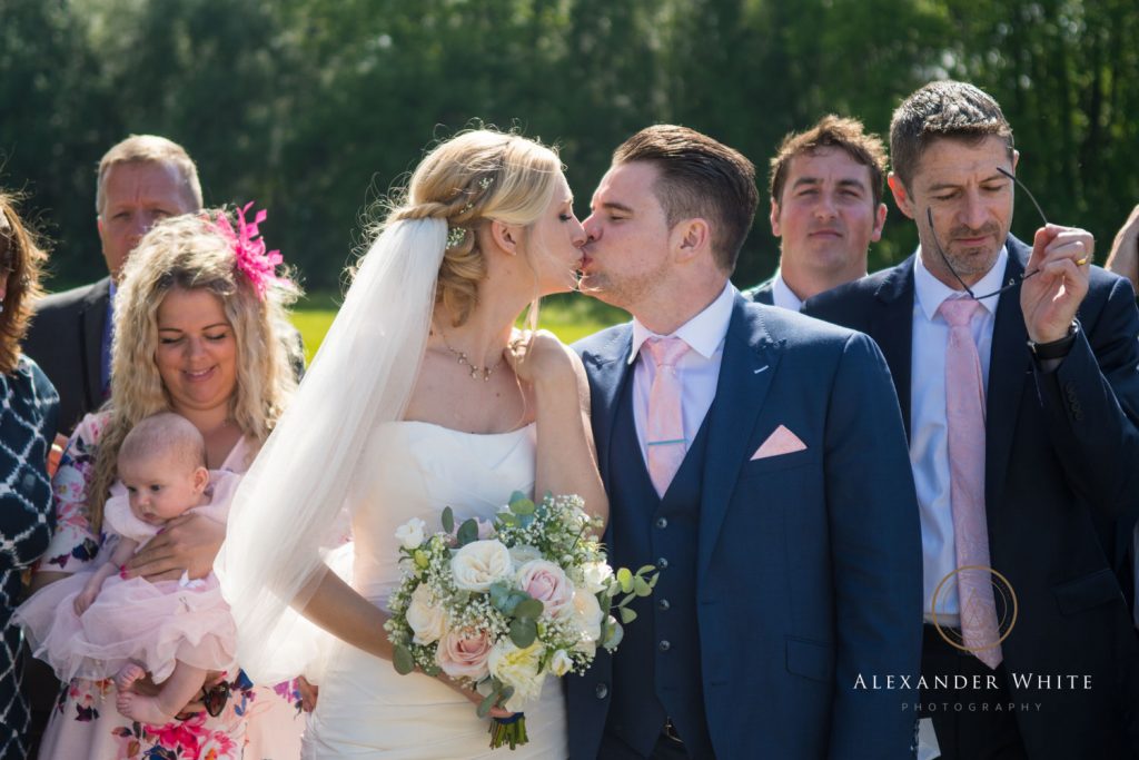 Bride and Groom kiss during a group photo