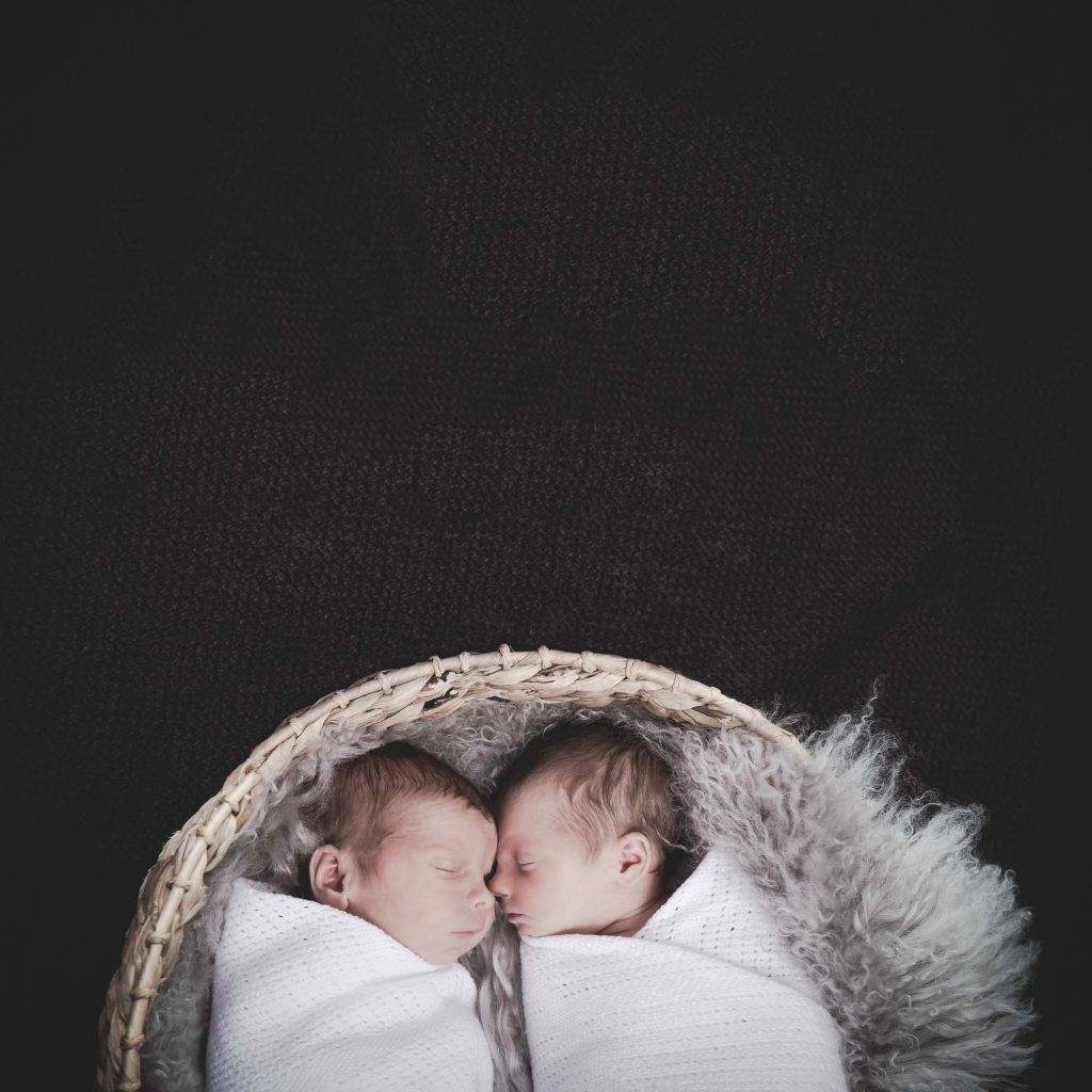 Photograph of twins asleep in a basket