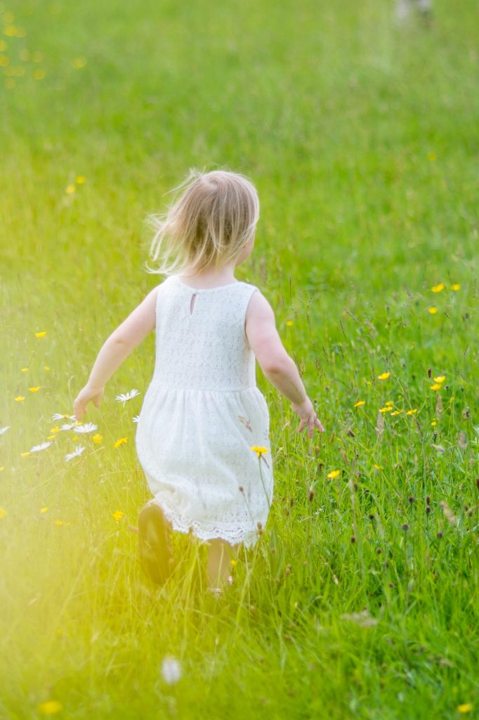 Young girl running through a field of wild flowers