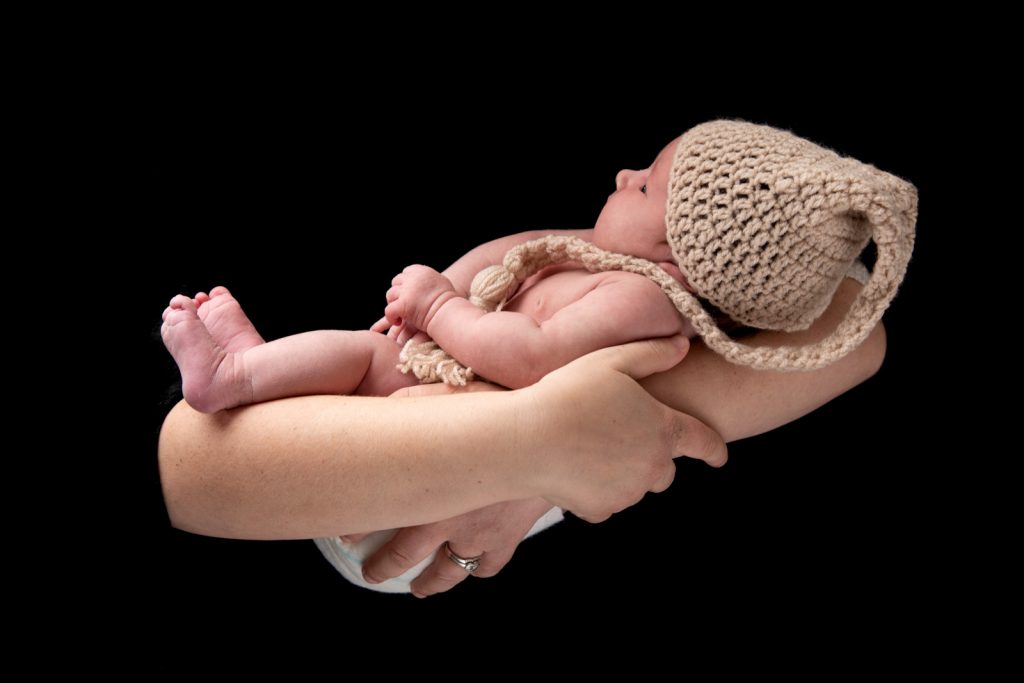 baby in mothers arms with a night cap on it's head