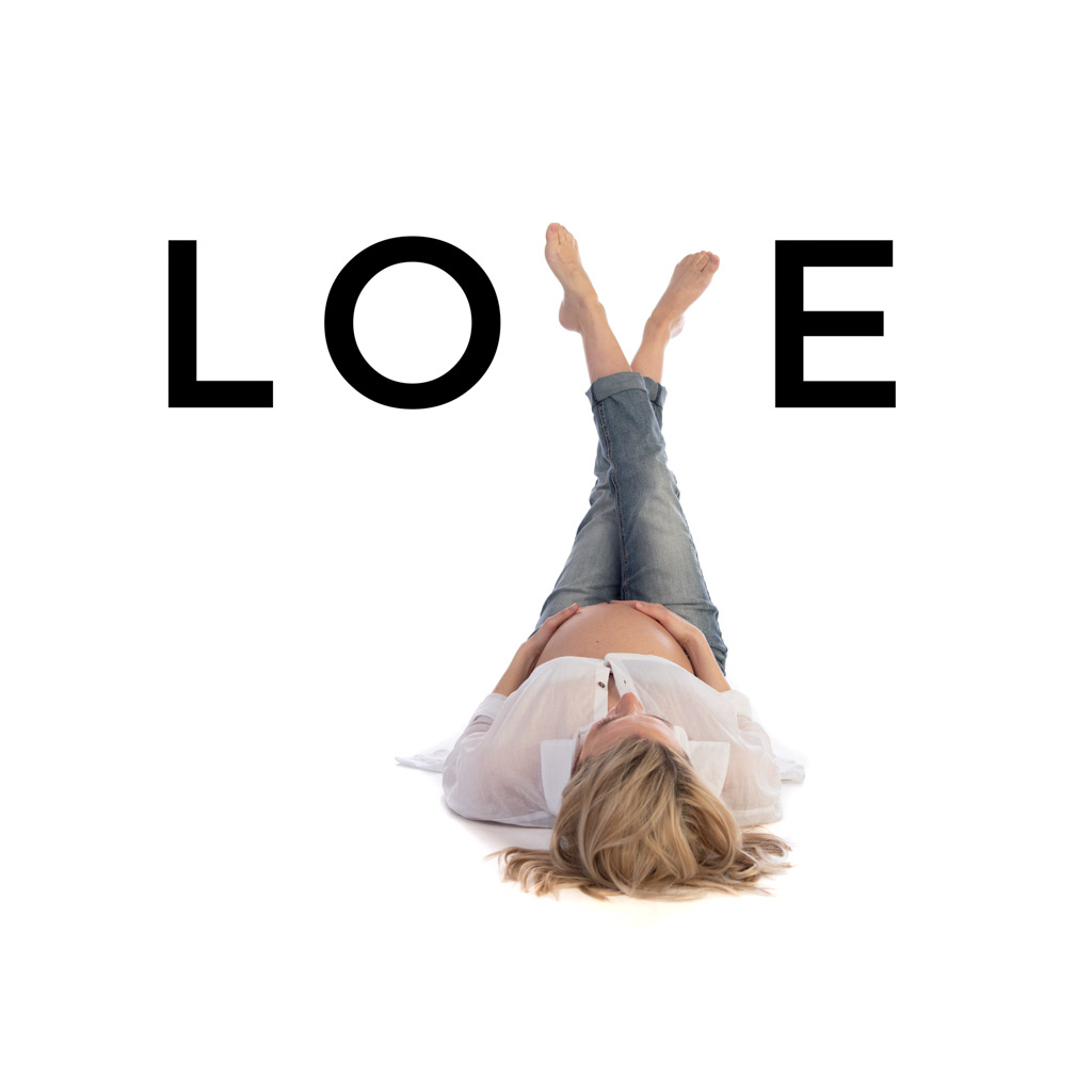 Maternity Photo of an expectant mum lying on the floor with her legs up spelling the word LOVE using her crossed legs as the letter V