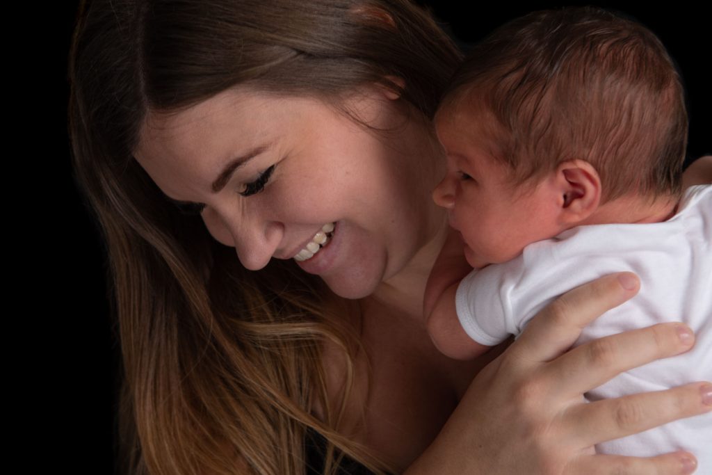 Mother holding her newborn baby in her arms and smiling