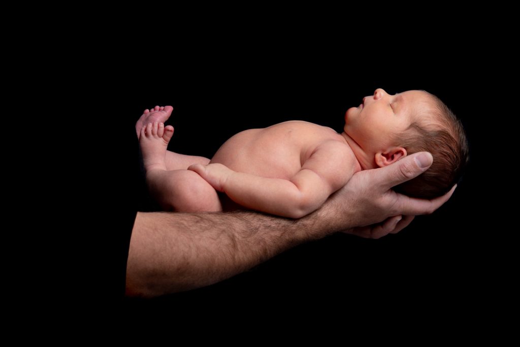 Newborn baby lying in his father's arms
