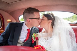 wedding photo of the bride and groom kissing in the back of a car