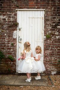 wedding photo of flower girls about to open a door