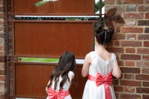 wedding photo of flower girls peeking through a door to spot their parents