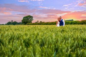 wedding photo of the bride and groom out in a field at sunset