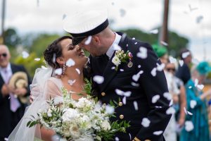 wedding photo of the bride and groom kissing surrounded by confetti