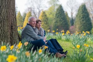 A couple sitting under a tree, surrounded by daffodils