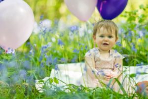 photo of a baby girl in a bluebell wood surounded by balloos