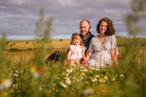 Young family maternity photo amongst the wildflowers