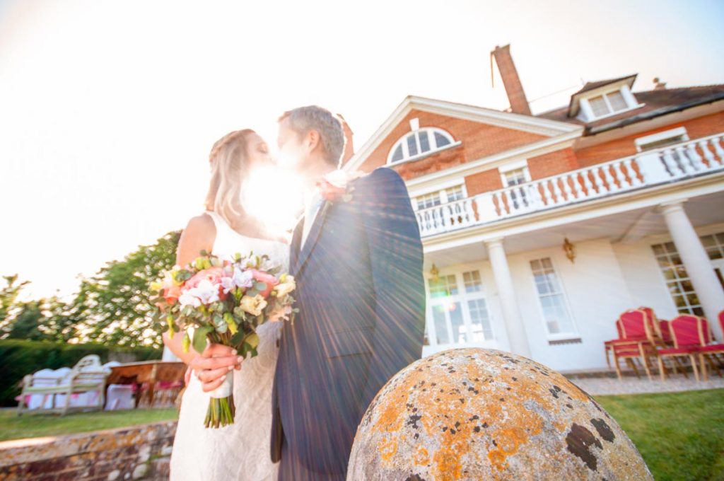Wedding photograph of couple kissing with sun streaming through between them