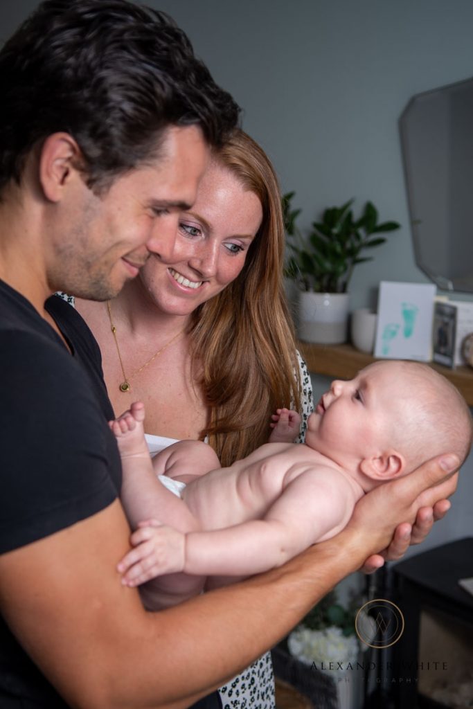 newborn baby photo with parents looking at the baby