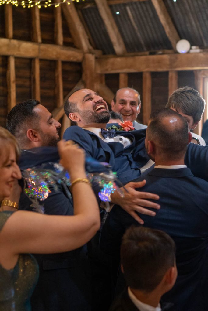 A wedding groom being lifted up in celebration by his groomsmen