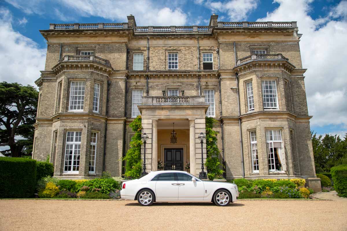 Photo of a grand wedding venue with wedding car out front