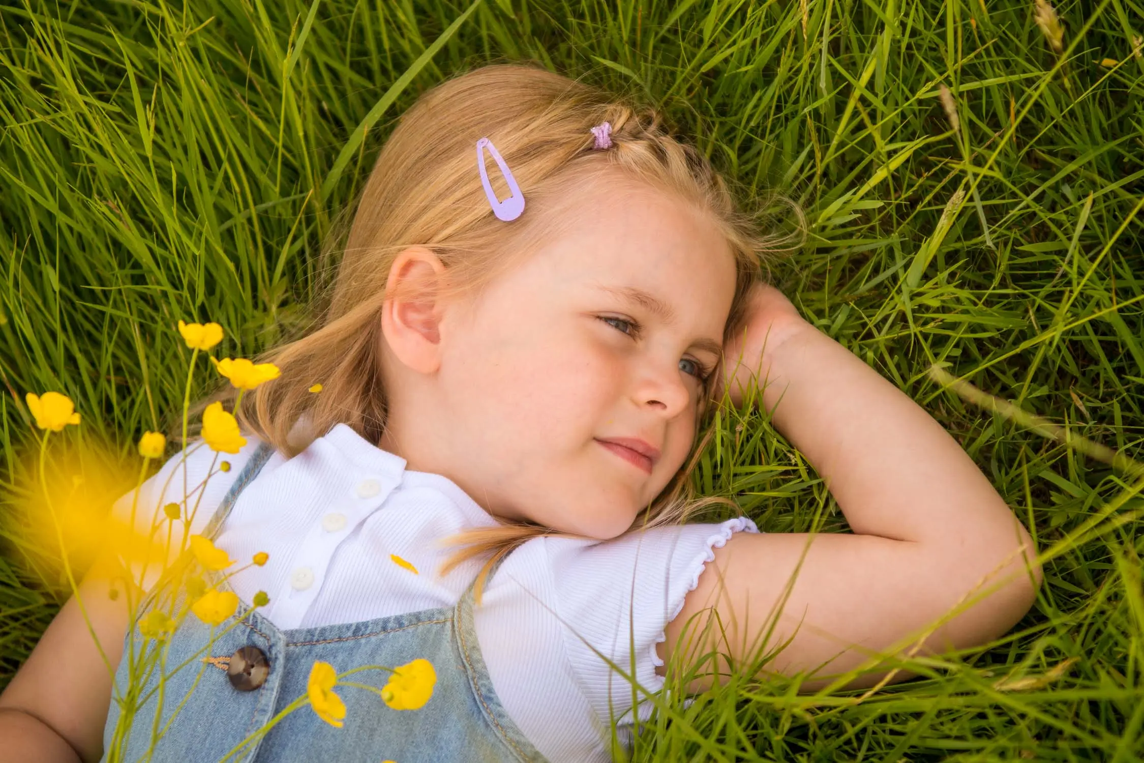 A young girl lying in the grass with wildflowers