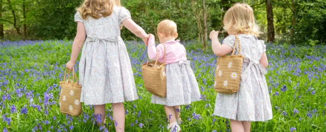 A family photograph of three young girls walking in a bluebell woodland
