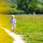 A young boy running through a wild flower meadow