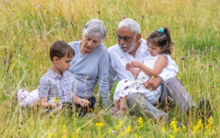 Two children sitting in a meadow with their grandparents