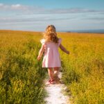 A young girl runs through a wildflower meadow