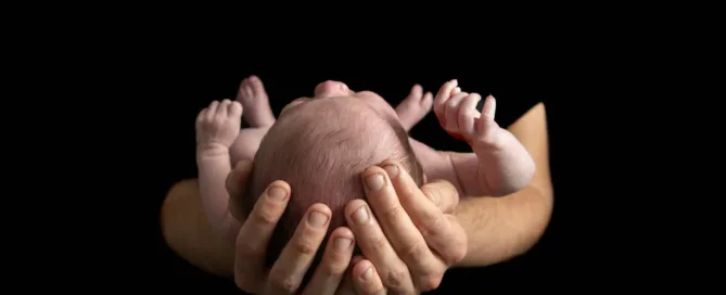 Newborn baby being held in her father's hands